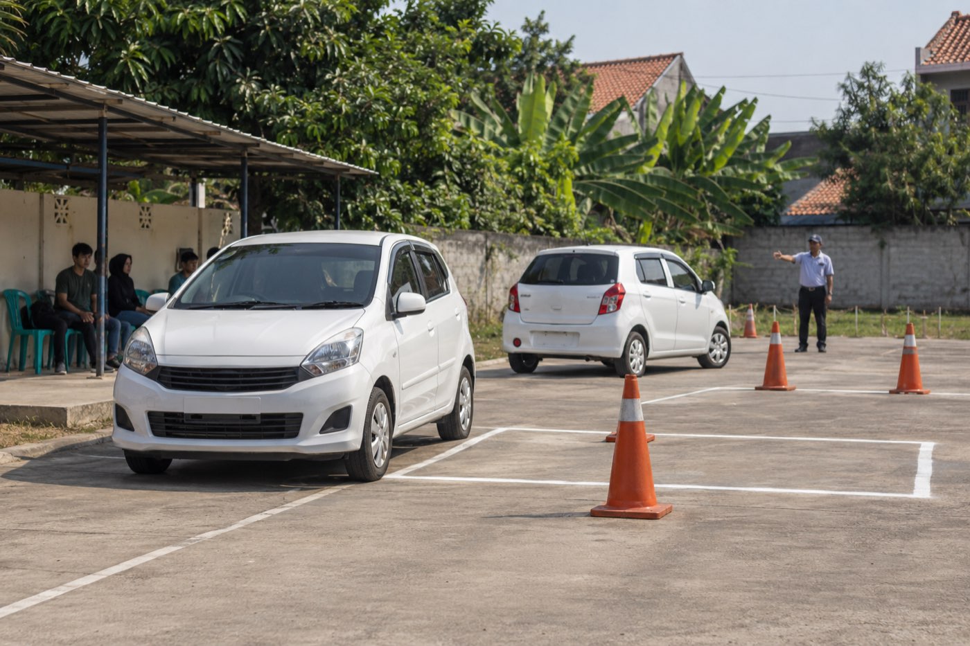 Halaman latihan sekolah mengemudi di Bekasi: dua mobil putih, kerucut oranye, dan petak parkir bergaris (foto ilustrasi AI)